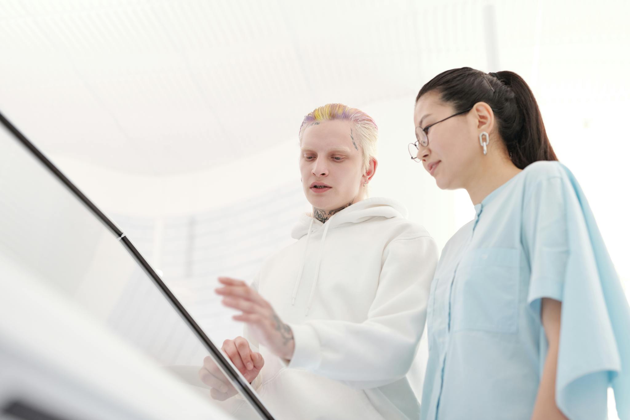 Two people engaged in a discussion, using a touchscreen in a modern white office.
